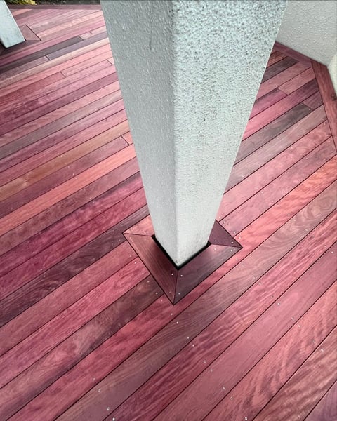 White cylindrical column base on red-brown wooden deck planks