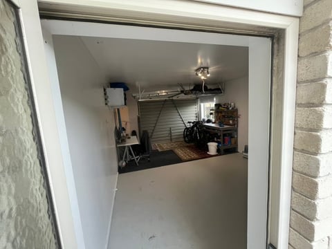 Interior view of a small storage room or closet with metal shelving, tools, and various items organized inside