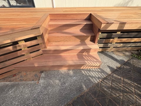 Wooden deck stairs under construction with cut-out steps and black metal stringers visible from above
